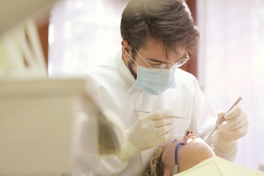 Dra Eva Maria Fuertes - Dentist in face mask conducting a dental examination with tools in clinic setting.